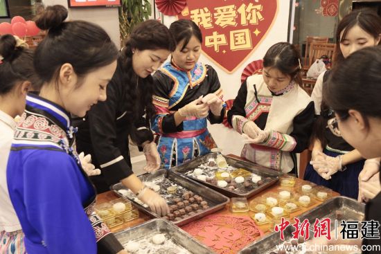 图为少数民族学生包月饼共度中秋佳节。